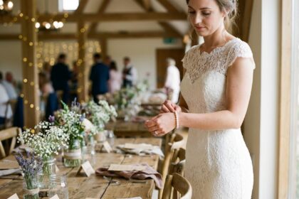 Jeune mariée en robe en dentelle ajuste un bracelet de perles